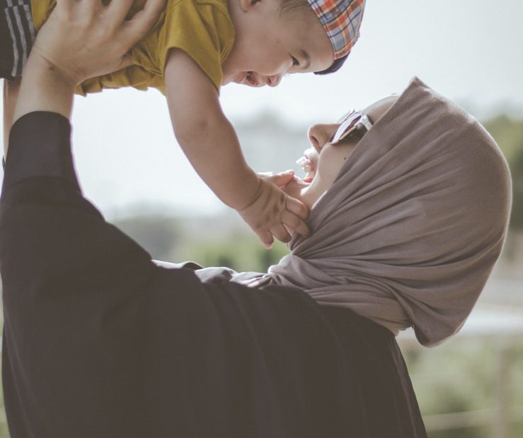 woman holding boy during daytime