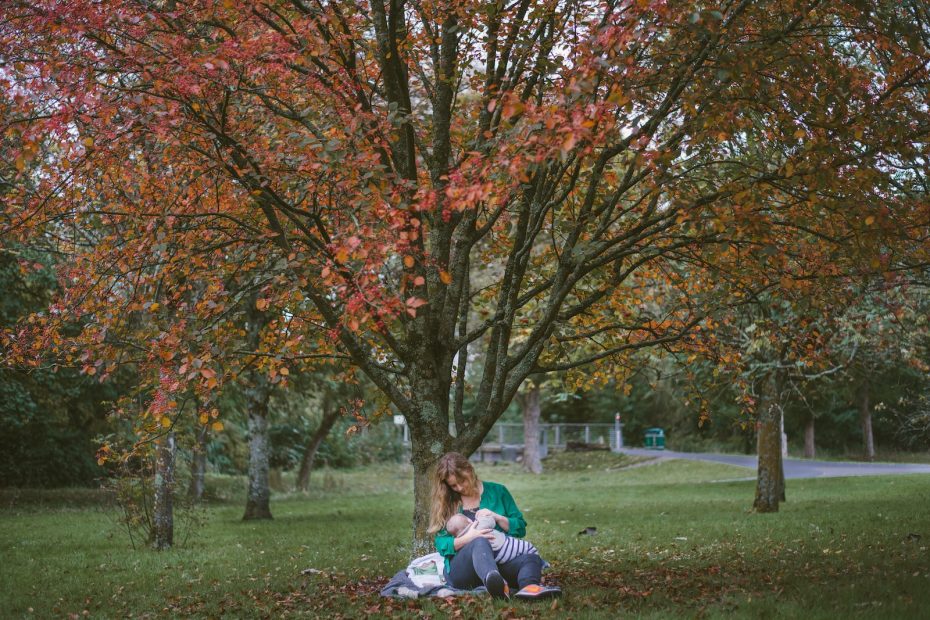 woman holding baby sitting under the tree